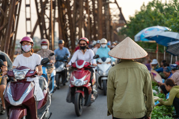 Vietnamese woman with traditional cone hat walking on Long Bien bridge busy street