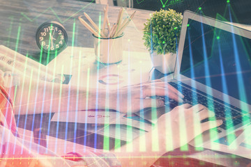 Double exposure of stock graph with businessman typing on computer in office on background. Concept...