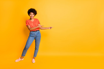 Copyspace full length body size photo of nice charming pretty sweet girl black presenting you something proposing wearing t-shirt jeans denim isolated with yellow vivid color background