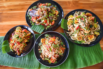 Papaya salad served on dining table / Green papaya salad spicy thai food on plate with fresh vegetables corn herbs and spices seafood shrimp crab noodles salted egg Som tum Thai menu Asian food