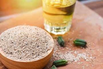 Sesame seeds in a wooden bowl and green leaf with sesame oil