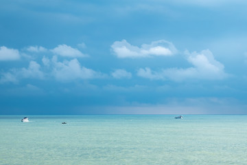 Blue sea and several boats on a cloudy day