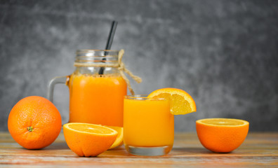 Orange juice in the glass jar and fresh orange fruit slice on wooden table - Still life glass juice on dark