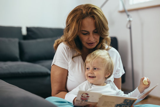 grandmother looking picture book with her grandson at home