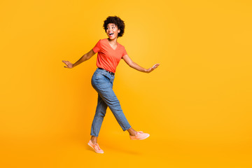 Fototapeta na wymiar Full length body size photo of charming cute cheerful wavy curly sweet attractive black girlfriend wearing t-shirt jeans denim going side profile to you isolated over yellow vivid color background