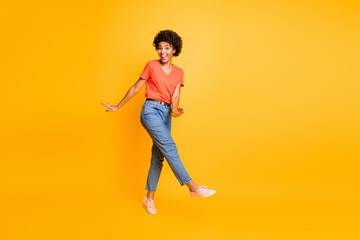 Fototapeta na wymiar Full length body size turned photo of cheerful charming cute carefree clubbing girl dancing on the go rejoicing excited of sales wearing jeans denim orange t-shirt isolated vivid color yellow
