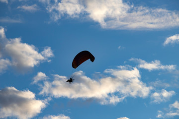 Paraglider silhouette over blue sky.
