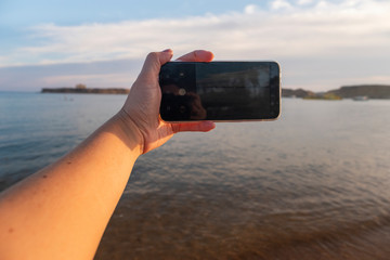 Smartphone in hand. Tropical sea on a background