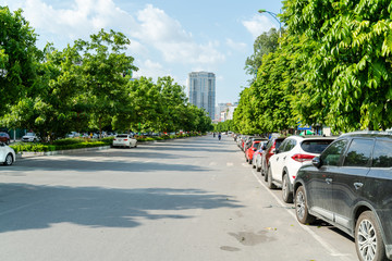 Cars parked on the urban street side, with green tree line. Green city concept