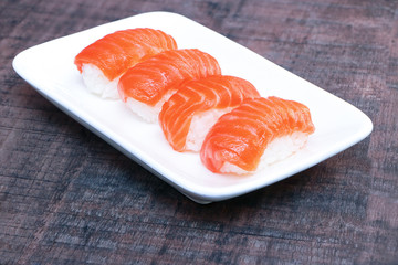 Salmon sushi in white plate on wood table background..