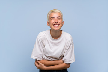 Teenager girl with white short hair over blue wall smiling a lot