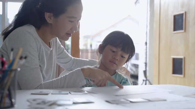 happy mother teaching her daughter the basic to read and write at home. toddler kindergarten student