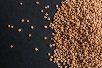 Spice mustard seeds scattered on a black background