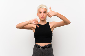 Teenager girl with short hair over white wall making good-bad sign. Undecided between yes or not