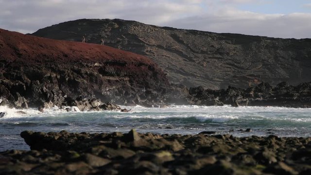 Shot of the waves on Lanzarote Island in the Canary Islands. White sparkling water, ocean and black lava rocks. Static shot.