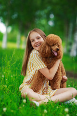 Little girl with a brown poodle dog, outdoor summer