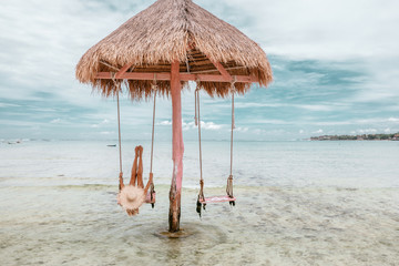 Girl on beach swing on Bali island