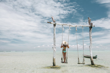 Girl on beach swing on Bali island