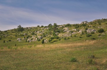 Obraz premium Sunny summer landscape. Beautiful rocks between the green hills.