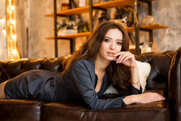 young woman in elegant dress laying on the sofa over christmas interior background