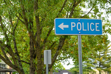 Police sign with arrow. On a green tree background.