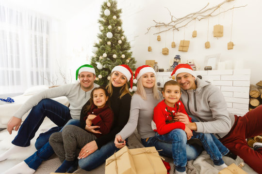 Closeup portrait of big happy family with Santa Claus lying down near Christmas tree, holiday celebration, joy and happiness concept