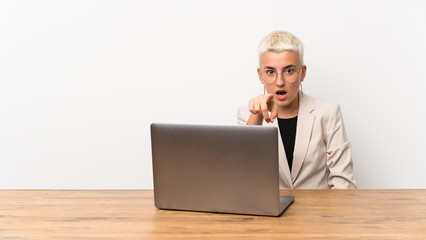Teenager girl with short hair with a laptop surprised and pointing front