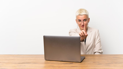 Teenager girl with short hair with a laptop showing and lifting a finger