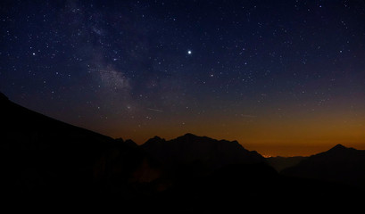 Shooting stars fly across the evening sky spanning above the serene Julian Alps.