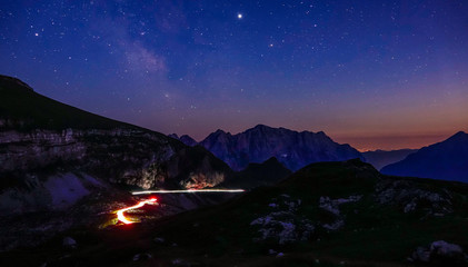 TIMELAPSE: Blurry car lights moving along mountain road under the starry sky.