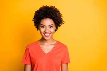Photo of attractive cheerful cute funky girlftiend smiling toothily wearing orange t-shirt isolated over yellow vivid color background