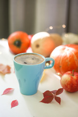 Blue cup of coffee with orange pumpkins in background