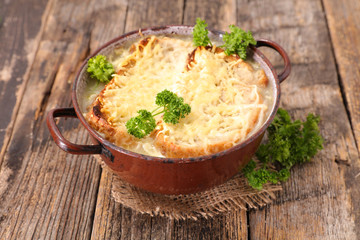 onion soup with bread slice and gruyere on wood background