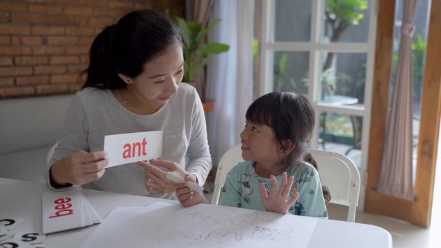 happy mother teaching her daughter the basic to read and write at home. toddler kindergarten student