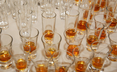 small shot glasses of cognac, whiskey or brandy or rum on a table in a restaurant. Background, pattern.