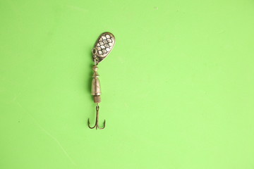 Teaspoon-shaped fishing lure on color background