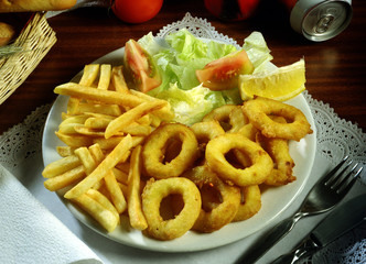 Plato de calamares a la romana con patatas fritas y ensalada.