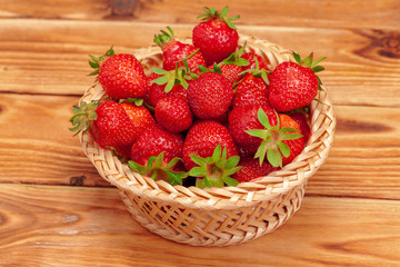 Basket of strawberry harvest on wooden table close up