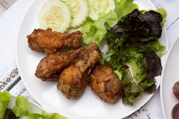 Close up top view of deep fried chicken on white plate surved with salad vegetable.