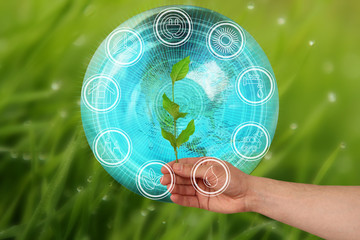 branch in hand on a beautiful autumn background model of the planet Earth and environmental protection elements icons, environmental concept, close-up