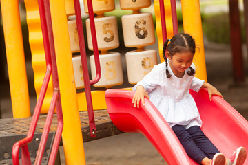 An Asian girl plays a slider on the playing field, creating development