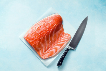 Fresh salmon slice on a wooden cutting board with a chef's knife on the table. cooking recipe. food...