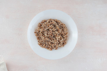 Buckwheat porridge on a white plate, light background.