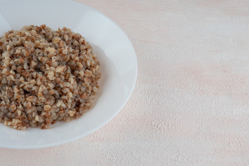 Buckwheat porridge on a white plate, light background.