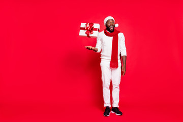 Full body photo of funny dark skin man offering cool x-mas prices throwing giftbox up air amazing...