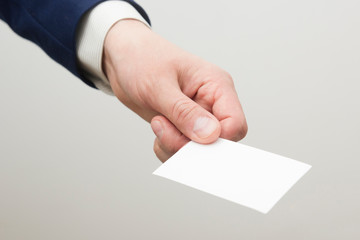 Hand holding white business card on white background.