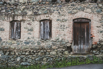 Fototapeta na wymiar Old wooden door in stone wall - abandoned house in Dilijan, Armenia