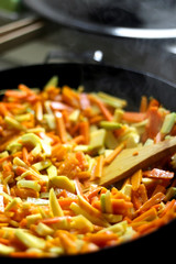 Cooking carrot, pumpkin, zucchini nad leek in wok. Selective focus, close-up.