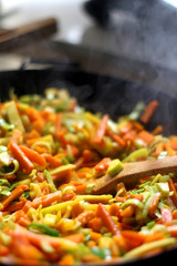 Cooking carrot, pumpkin, zucchini nad leek in wok. Selective focus, close-up.