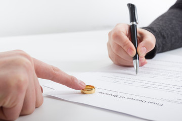 Divorce concept. Hands of wife, husband signing decree of divorce, canceling marriage, legal separation documents.